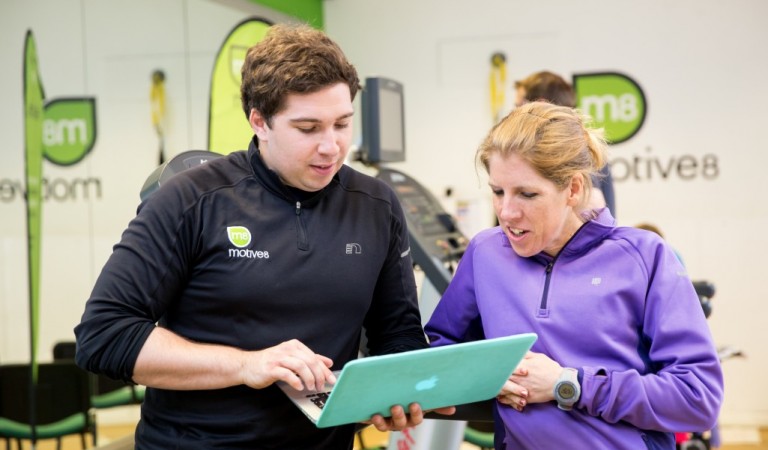 Male course tutor checking a laptop with a learner