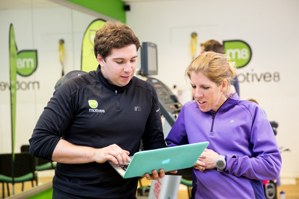 Male course tutor checking a laptop with a learner